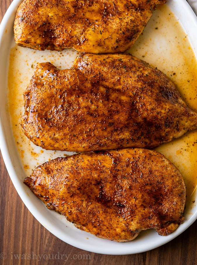 White plate with baked chicken and juices