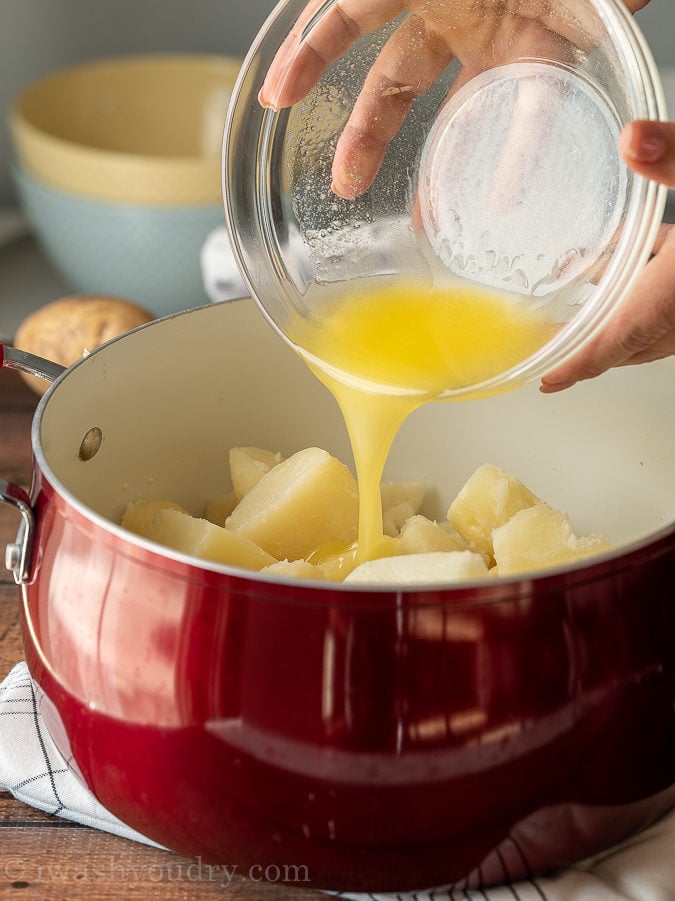Pour warm milk and melted butter into the cooked potatoes