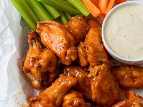 Saucy Buffalo Wings in basket with celery and carrots and a side of ranch dressing
