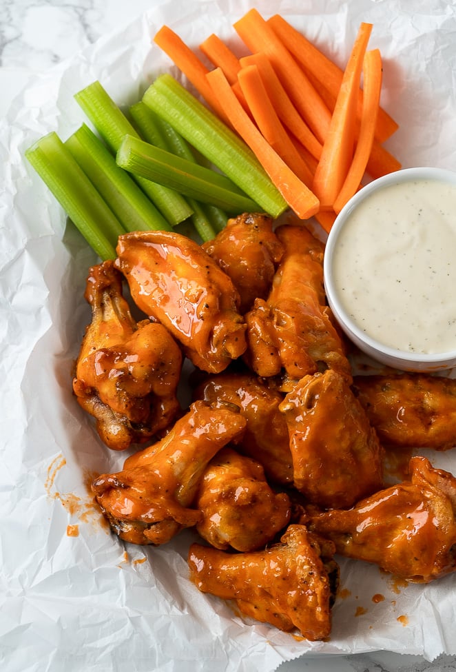 Saucy Buffalo Wings in basket with celery and carrots and a side of ranch dressing