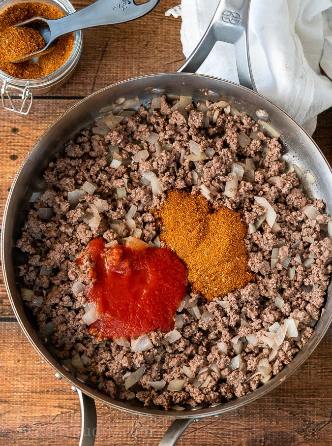 Brown ground beef and onions in a skillet with tomato sauce and taco seasoning.