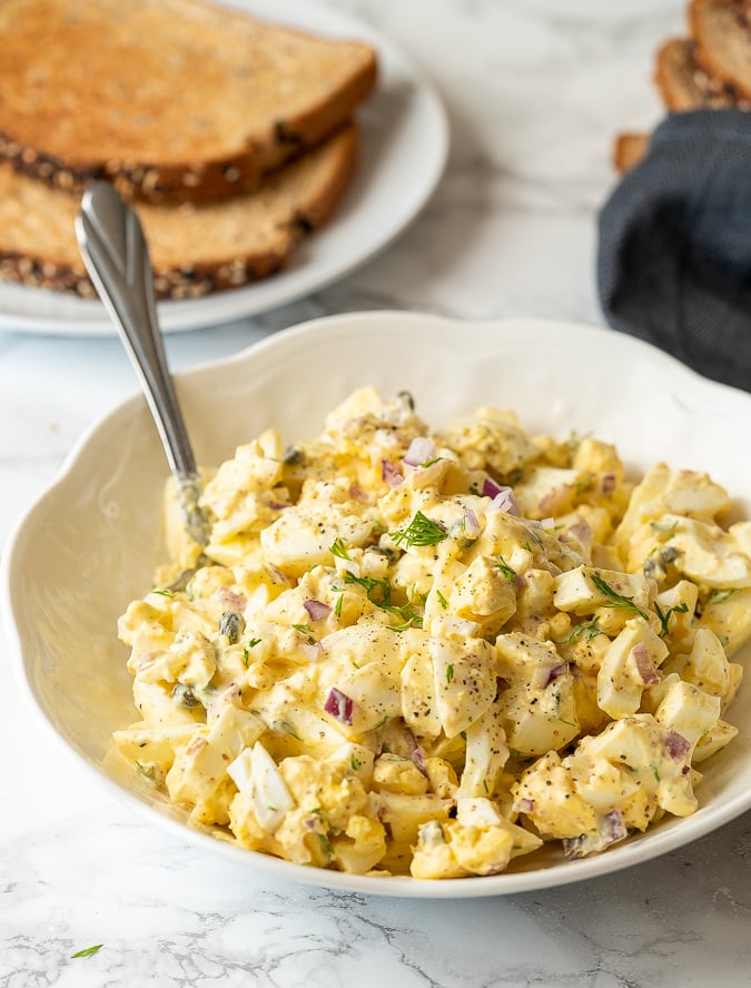 Egg Salad Sandwich Filling in a white bowl with fresh dill on top