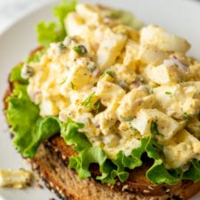 Lemon Caper Egg Salad Recipe on top of green lettuce and toasted bread.
