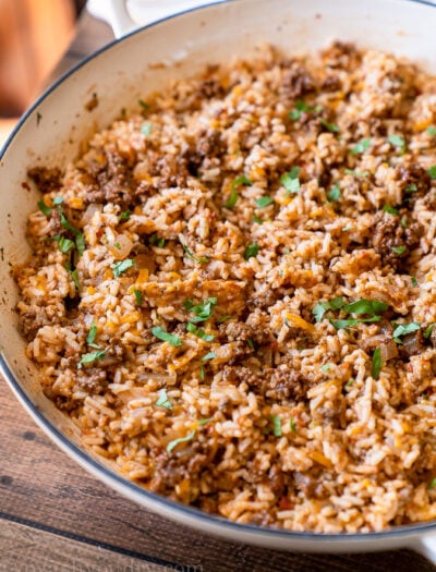 Close up shot of cheesy taco rice with bits of taco meat, gooey cheese and fresh cilantro on top.
