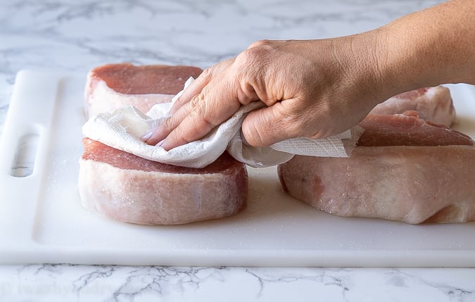 Pat dry the pork chops with paper towels before seasoning and baking in the oven.