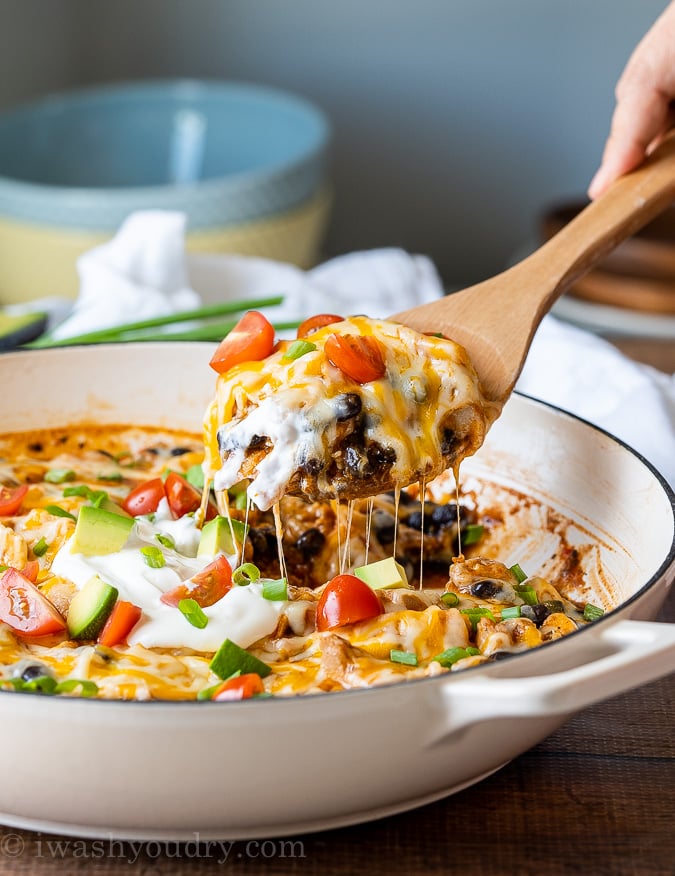 Spoonful of hearty Black Bean Enchiladas in a white pan.