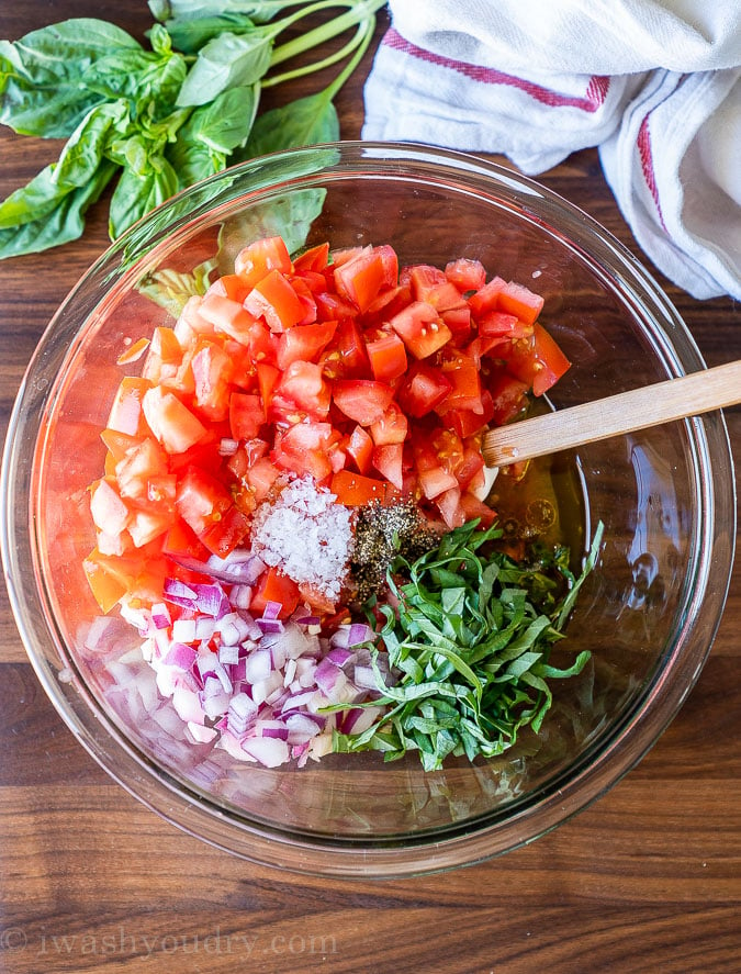 Tomato Salad ingredients with fresh basil and onion in a large bowl, ready to combine.