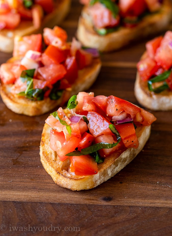 Close up image of simple bruschetta on top of a piece of toasted baguette bread.