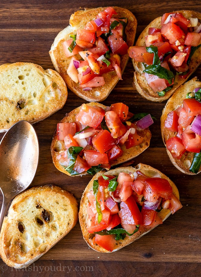 Slices of toasted baguette with fresh tomato bruschetta on top.