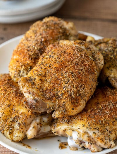 Oven Roasted Chicken Thighs on a white plate with seasoning on top.