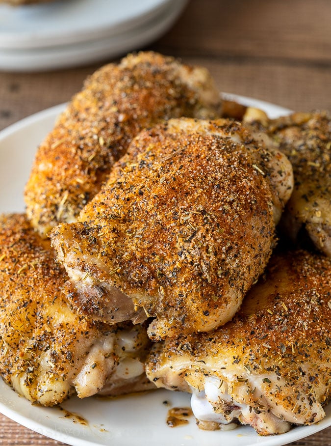 Oven Roasted Chicken Thighs on a white plate with seasoning on top.