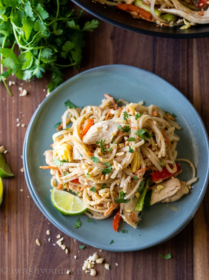 Simple Chicken Pad Thai recipe on a blue plate with lime wedge.