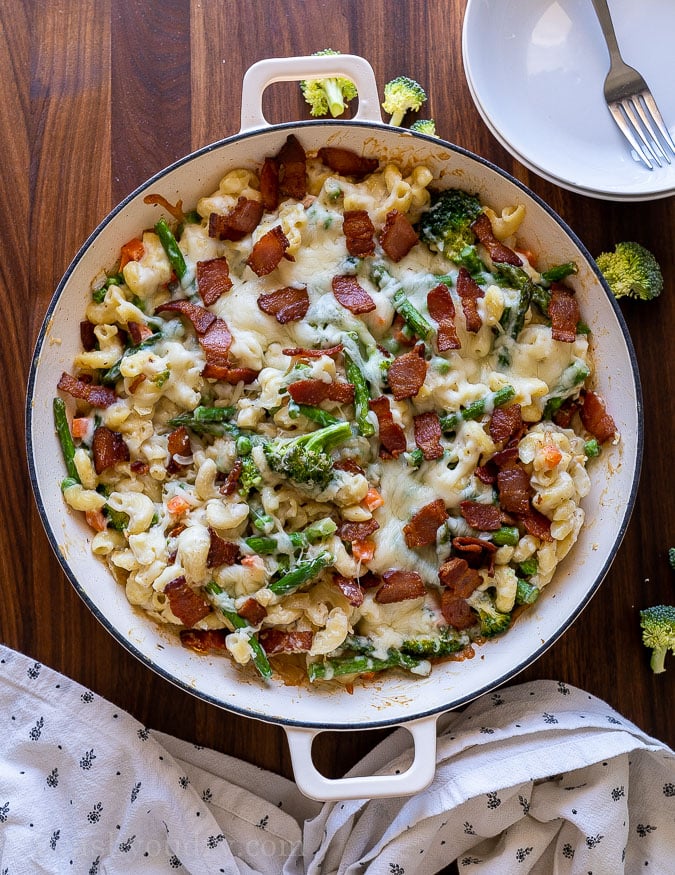 Hot skillet full of white cheddar macaroni and cheese with veggies.
