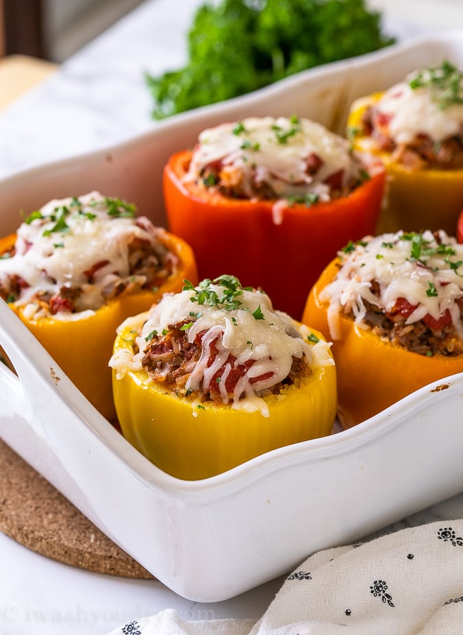 Casserole dish filled with stuffed peppers topped with cheese.