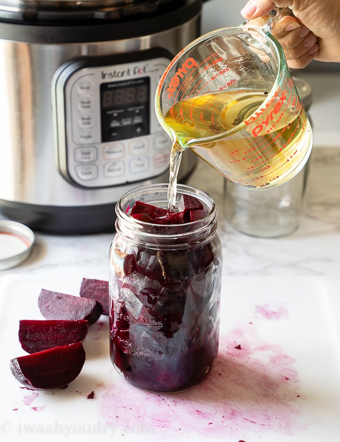 Adding brine to cooked beets in mason jar.