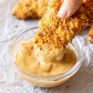 Dipping crispy chicken tenders in chick fil a sauce.