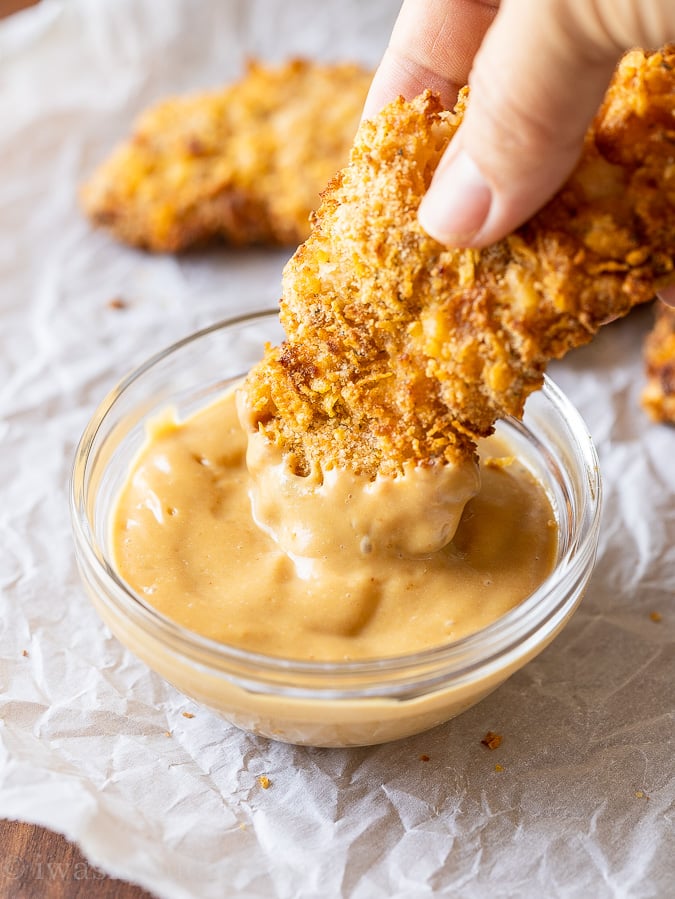 Dipping crispy chicken tenders in chick fil a sauce.