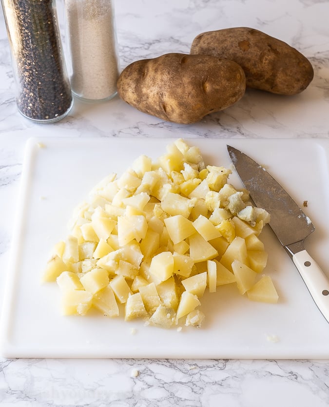 Diced cooked potatoes on a cutting board.