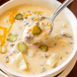 Spoonful of Cheeseburger Soup with dill pickles.