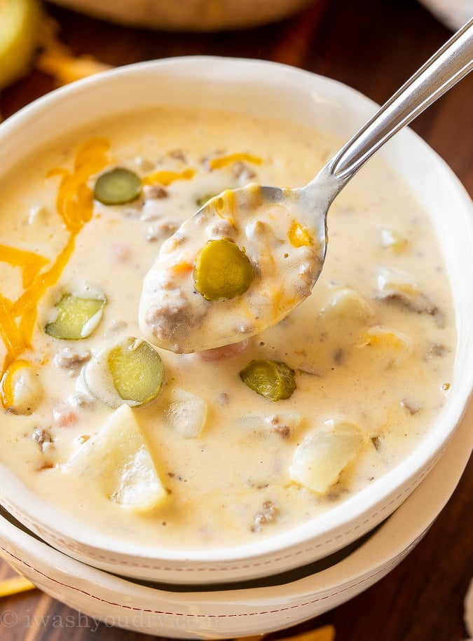 Spoonful of Cheeseburger Soup with dill pickles.