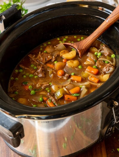 Beef stew in a slow cooker with wooden spoon
