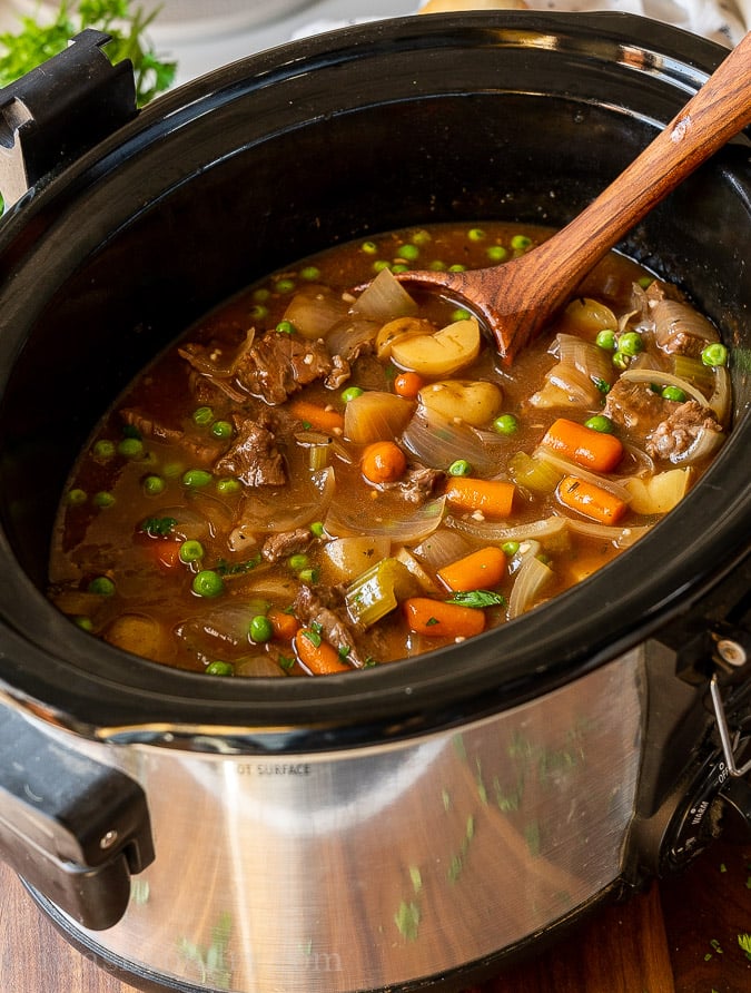 Beef stew in a slow cooker with wooden spoon