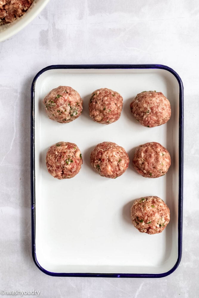 swedish meatballs lined up on white plate ready to cook.