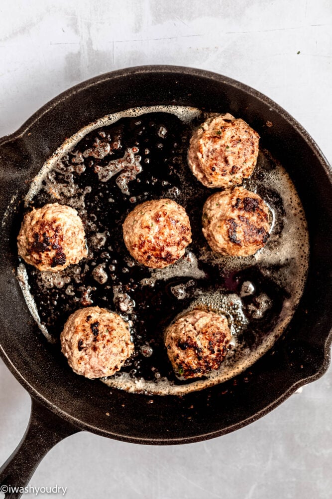 cooked meatballs in black skillet.