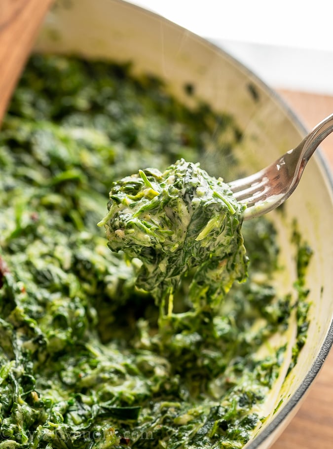 fork full of spinach over pan