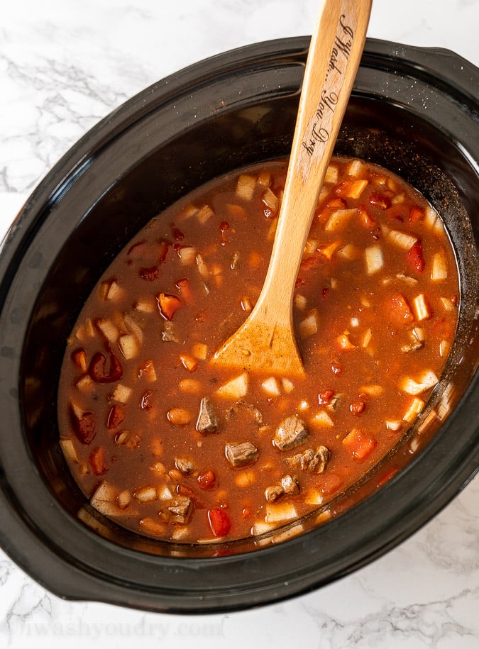 beef chili in slow cooker with wooden spoon