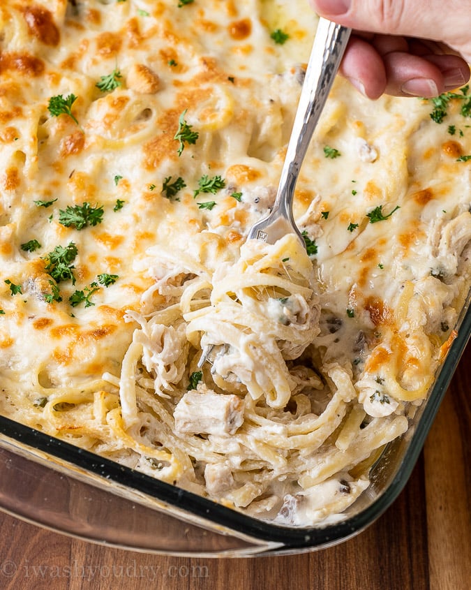 Fork full of twirled pasta in casserole dish