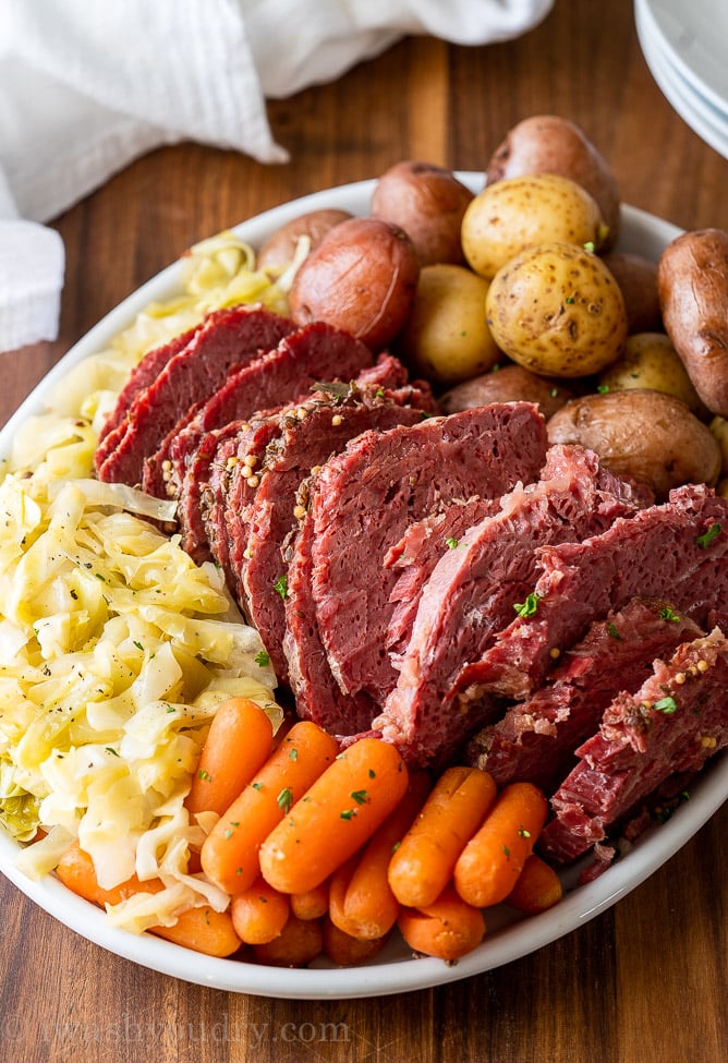 sliced corned beef with cabbage, potatoes and carrots on a white plate