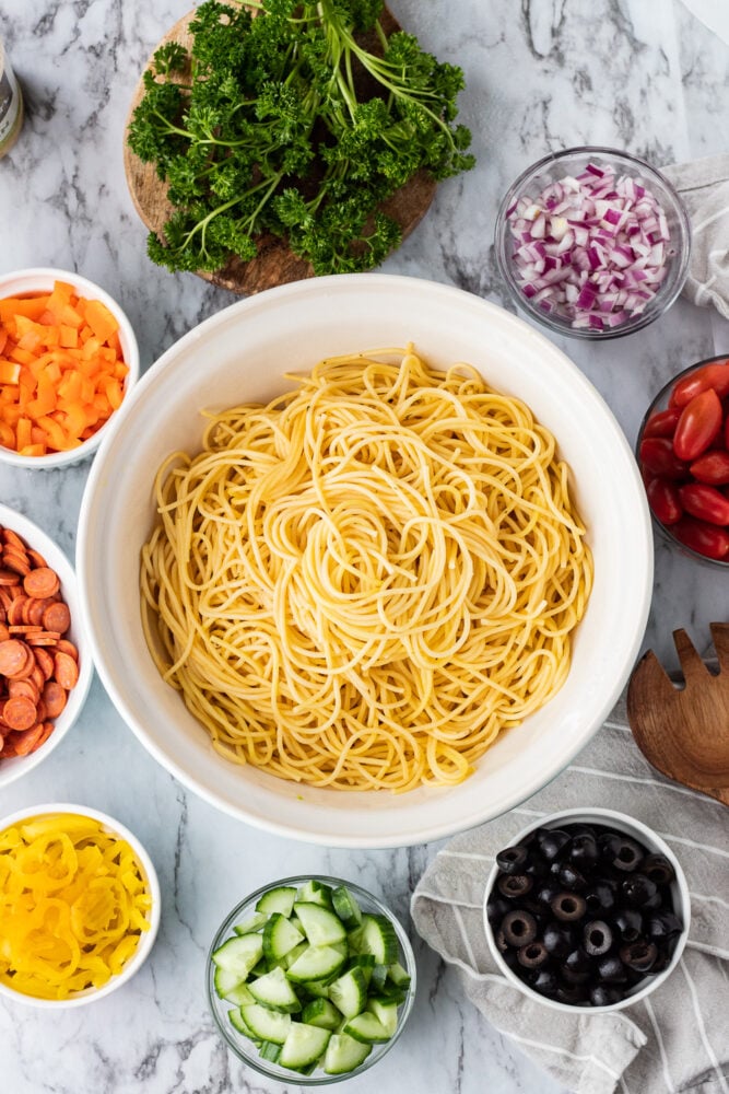 Bowl of Spaghetti noodles with bowls of veggies in a circle.