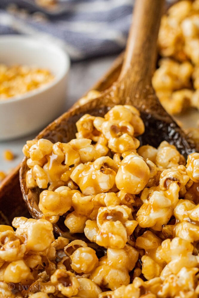 caramel corn in wooden spoon in metal pan. 