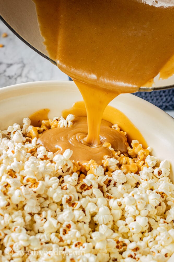 pouring caramel into bowl of popped popcorn 