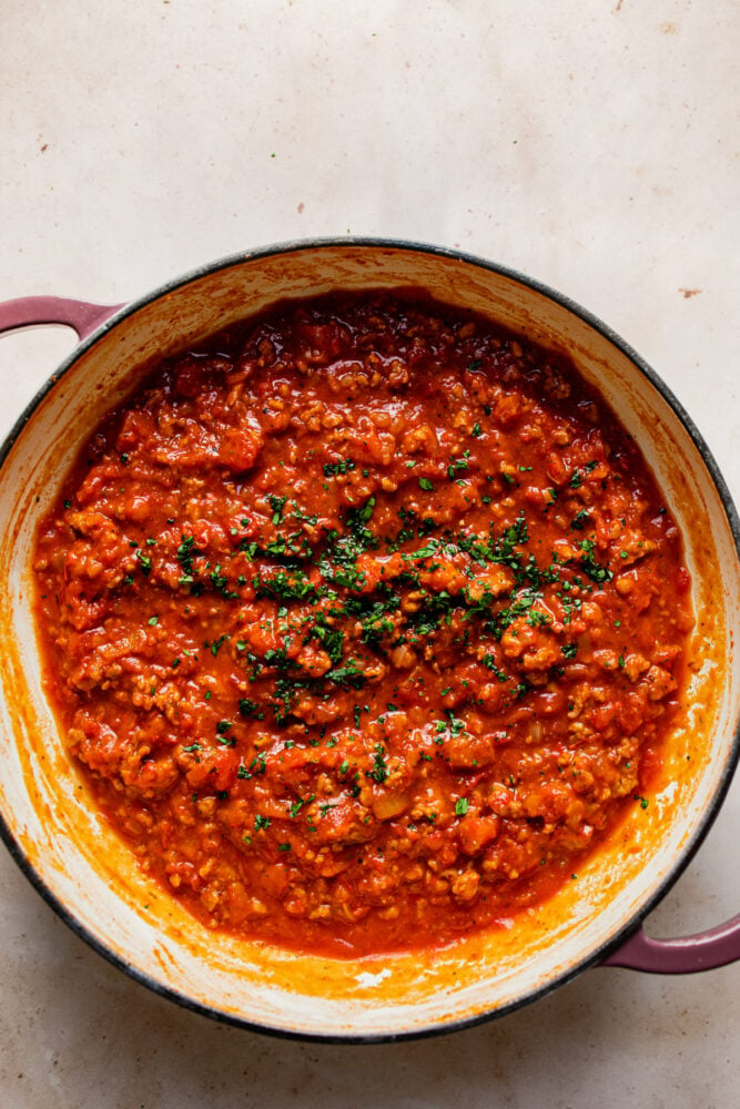 thick spaghetti sauce in pan with fresh herbs