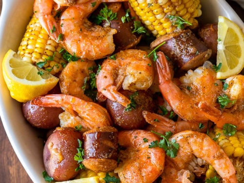 white dish filled with shrimp, potatoes, corn and sausage