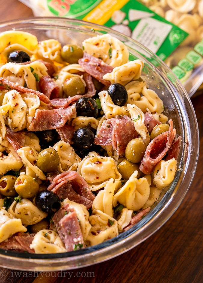 olive tortellini pasta and salami in bowl with dressing