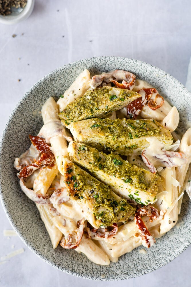 plate of creamy penne pasta with sliced chicken on top