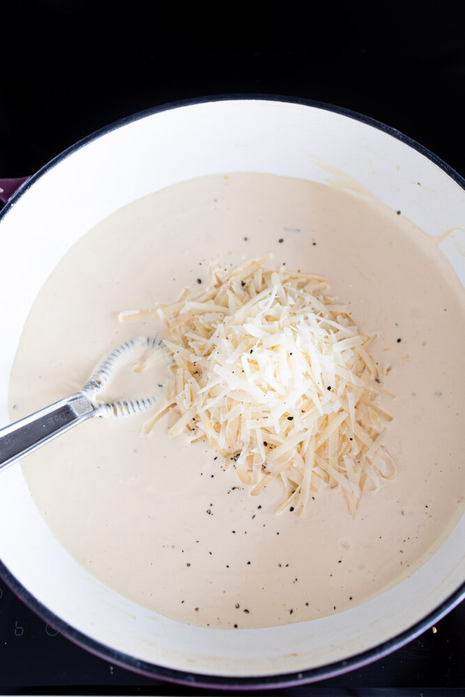 whisking together alfredo sauce with parmesan cheese