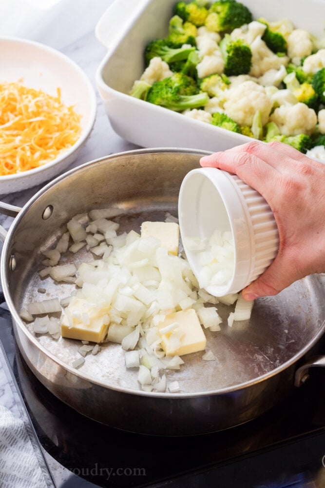 Pouring chopped onion into frying pan with butter. 