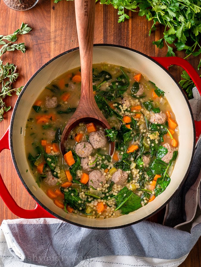 Soup with sausage, spinach and pasta in large pot with spoon