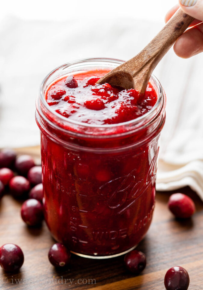 Sweet cranberry sauce in mason jar with spoon