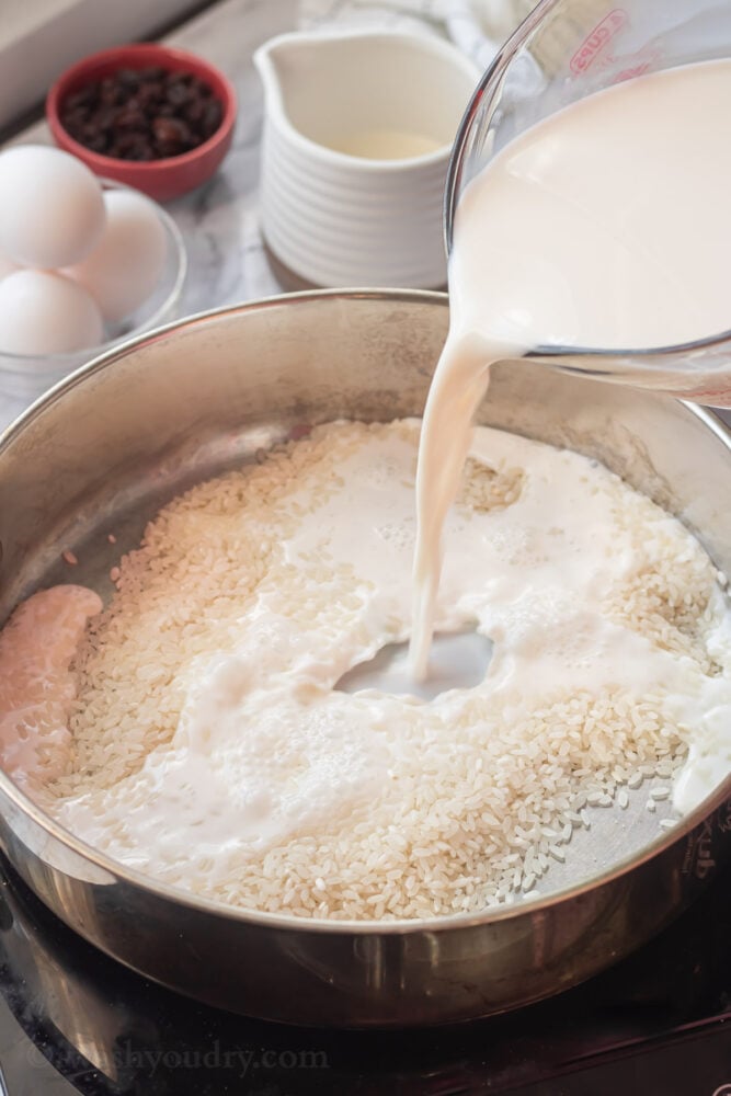pouring milk into metal pan of rice. 
