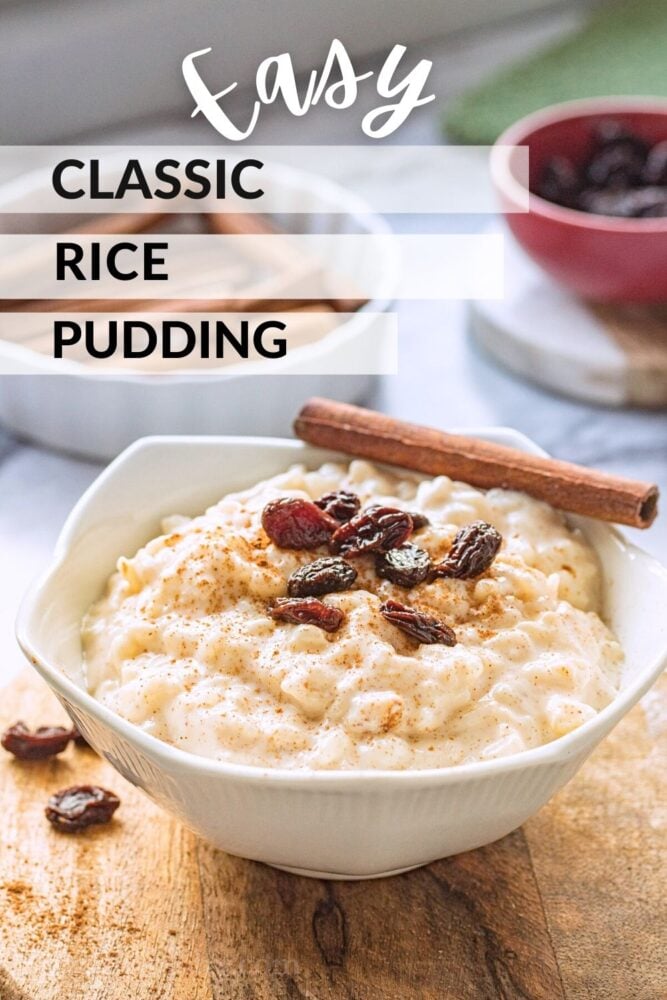 white bowl of cooked homemade rice pudding with raisins and cinnamon stick on cutting board. 