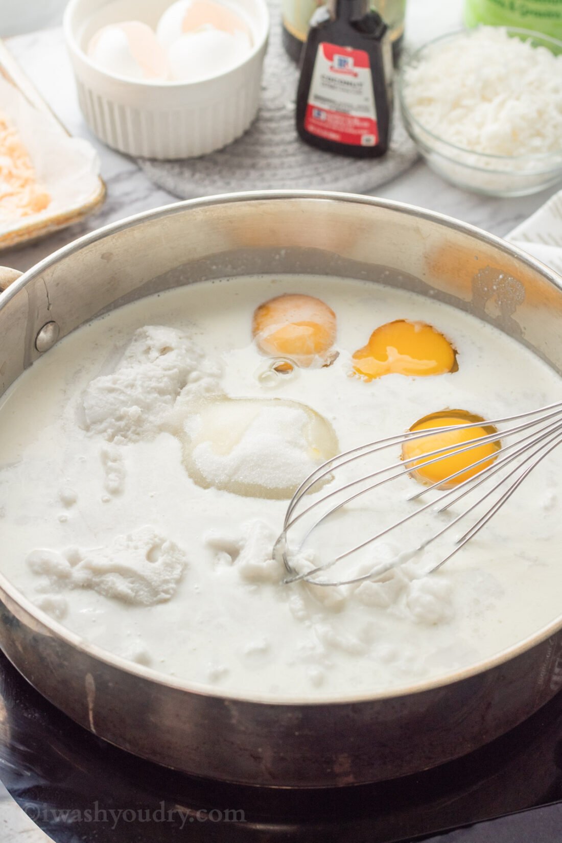 Eggs, cream, sugar and milk in pan with whisk. 