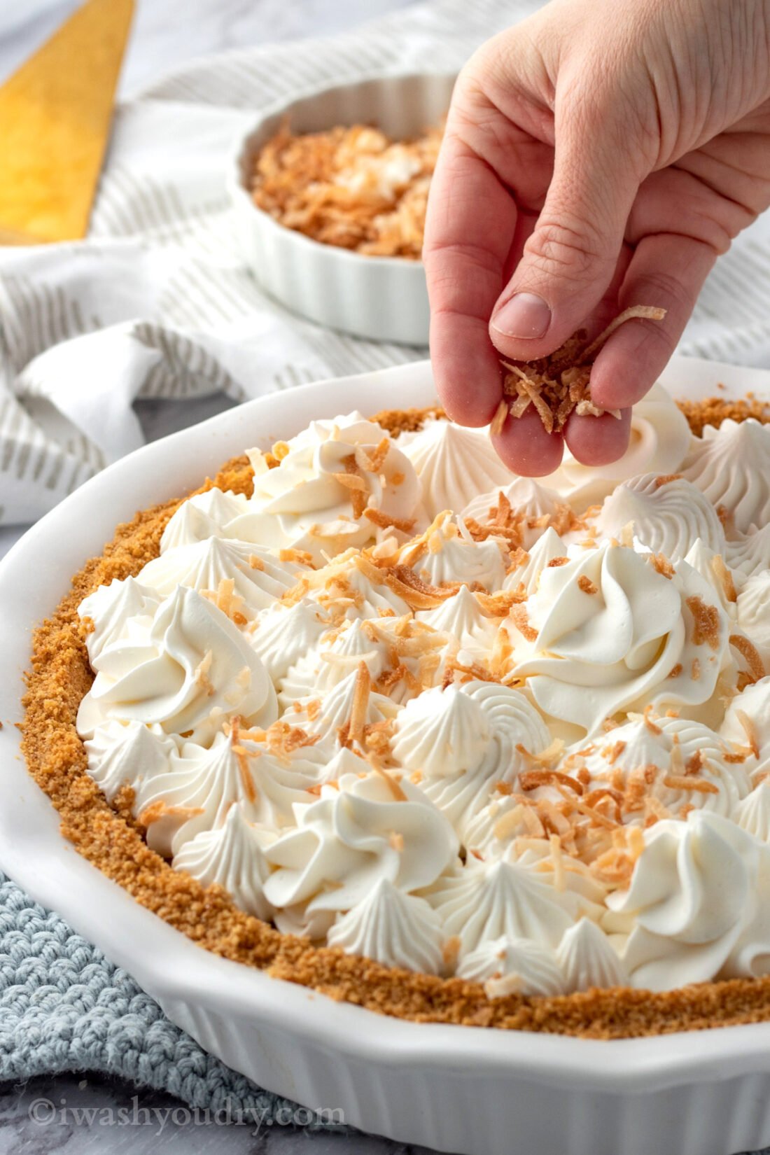 Sprinkling toasted coconut on pie.