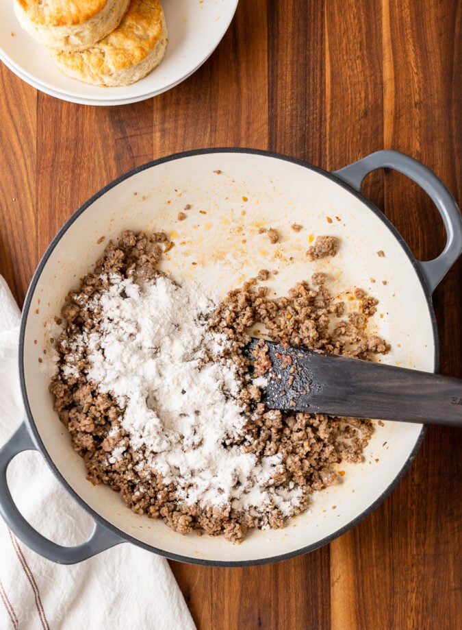 ground sausage with flour and wooden spoon in pan