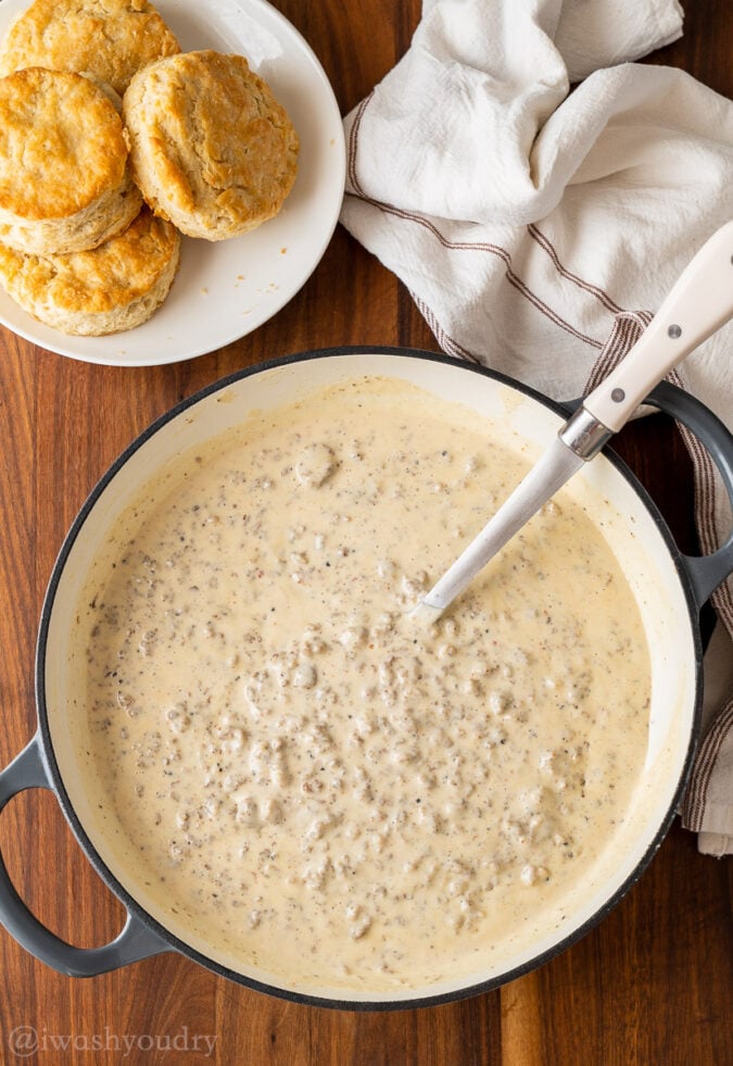 pan full of sausage gravy with spoon and biscuits