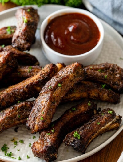 ribs on a plate with a bowl of bbq sauce